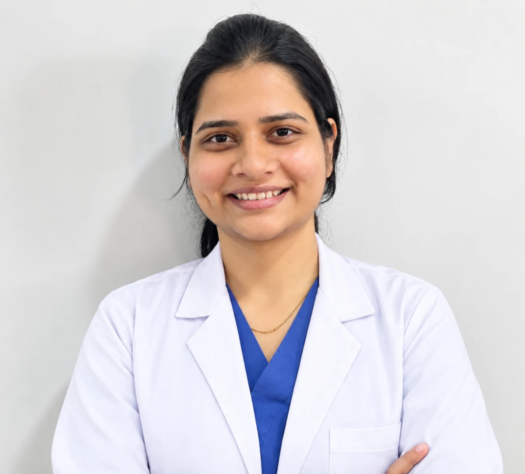 Dr. Saraswati Dundage wearing a white coat over blue dental scrubs