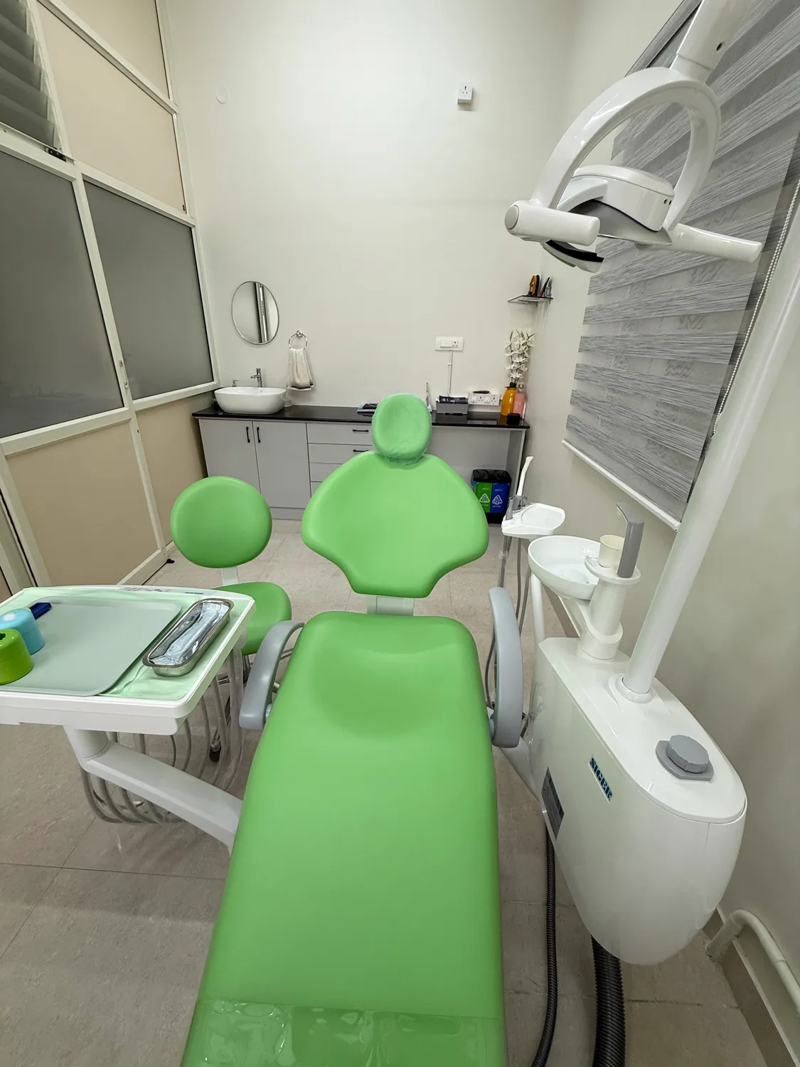 Green dental chair, overhead examination light and equipment in the treatment room