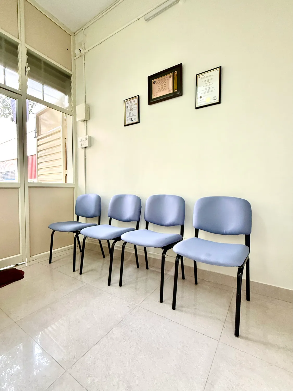 Three blue waiting chairs beside the windows inside Dundage Dental Clinic